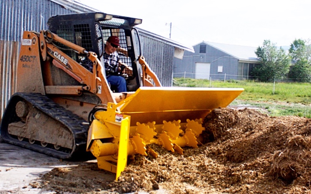 Student operating the compost turner at the college farm.